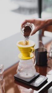 Premium 100% Arabica Bourbon coffee beans displayed in a rustic burlap sack and wooden scoop beside elegant coffee packaging and a bourbon barrel.
